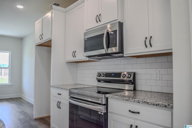 kitchen with light stone countertops, hardwood / wood-style floors, white cabinets, and stainless steel appliances