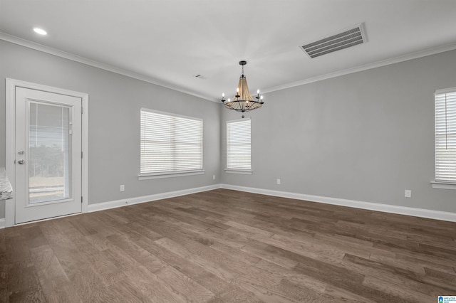 empty room with hardwood / wood-style floors, an inviting chandelier, and crown molding