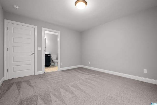 unfurnished bedroom featuring connected bathroom and light colored carpet