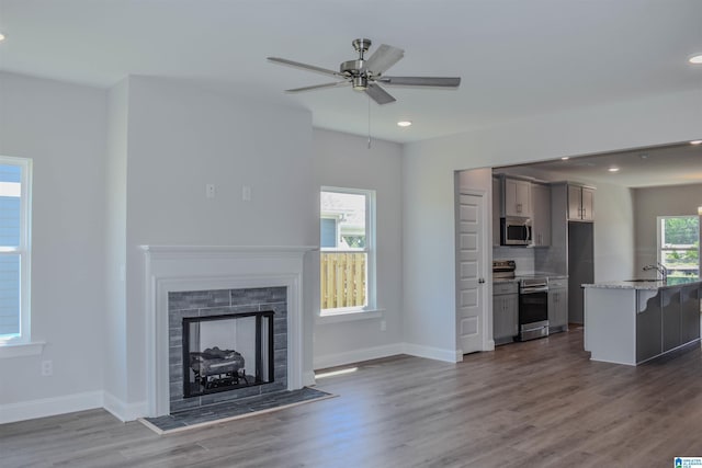 unfurnished living room featuring ceiling fan, a fireplace, and dark hardwood / wood-style floors