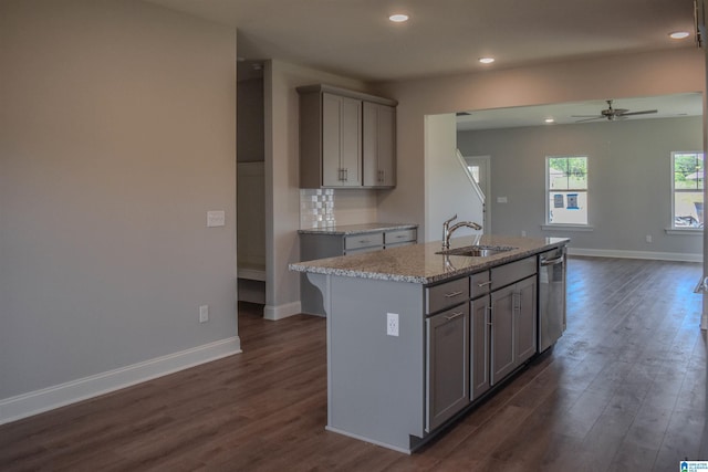 kitchen featuring light stone counters, sink, a kitchen island with sink, and tasteful backsplash