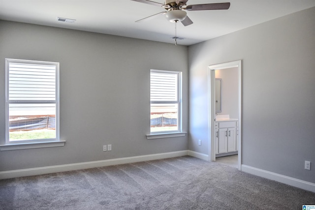 empty room featuring ceiling fan, plenty of natural light, and light colored carpet