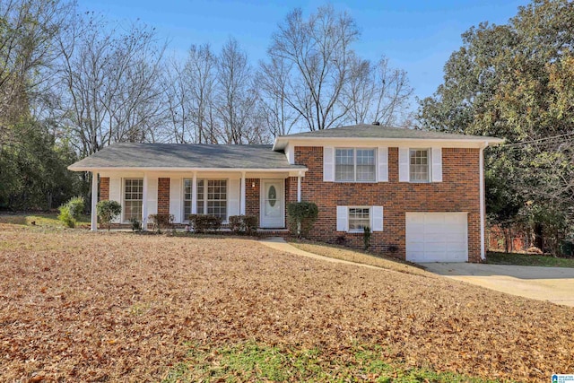 split level home with a garage, concrete driveway, and brick siding