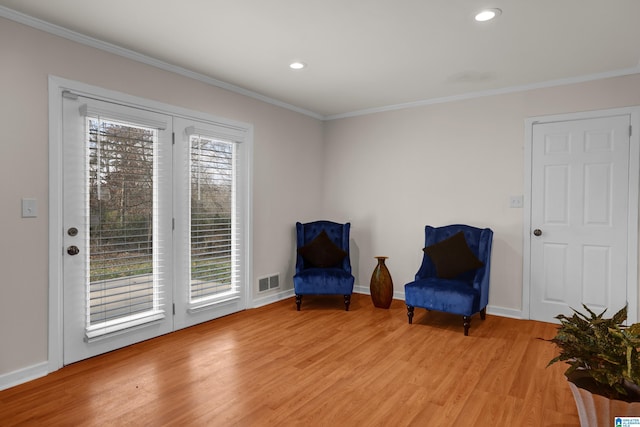 living area with light hardwood / wood-style flooring and ornamental molding