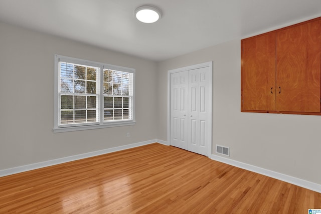 unfurnished bedroom with light wood-style floors, a closet, visible vents, and baseboards