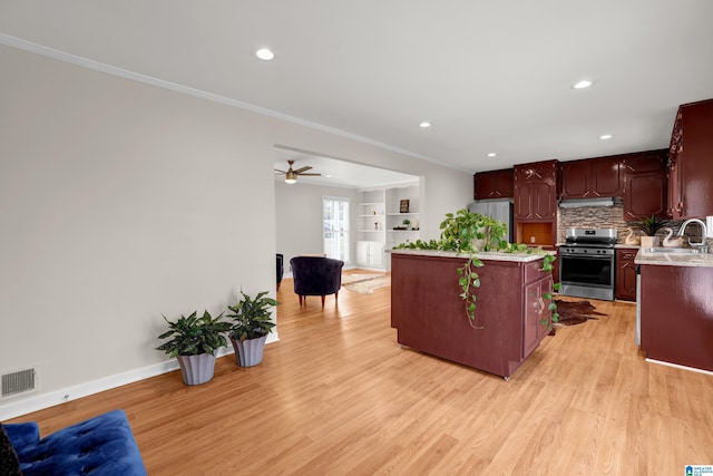 kitchen featuring built in shelves, ceiling fan, a center island, stainless steel appliances, and light wood-type flooring