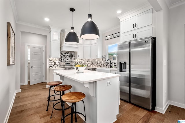 500 Avondale Ln, Pell City, AL 35128 - kitchen featuring appliances with stainless steel finishes, custom exhaust hood, white cabinetry, tasteful backsplash, and a kitchen bar