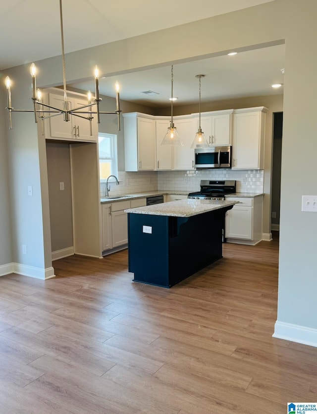 500 Avondale Ln, Pell City, AL 35128 - kitchen featuring stainless steel appliances, a center island, backsplash, white cabinetry, and light wood-style flooring