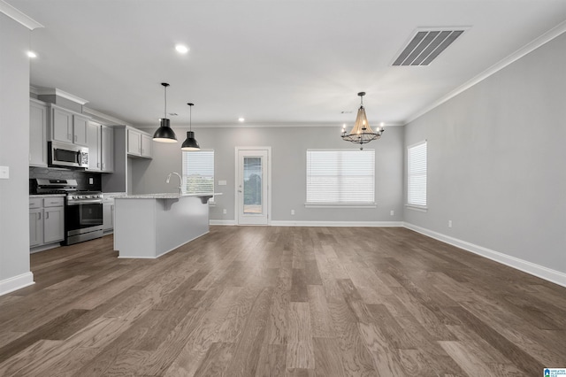 kitchen with a center island with sink, crown molding, hanging light fixtures, and appliances with stainless steel finishes