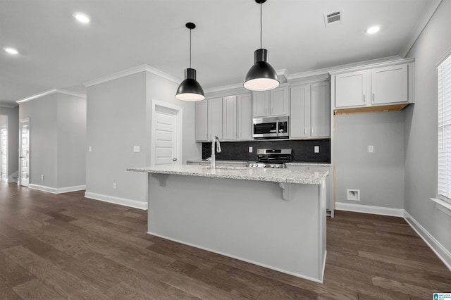 kitchen featuring decorative light fixtures, light stone counters, stainless steel appliances, and a kitchen island with sink