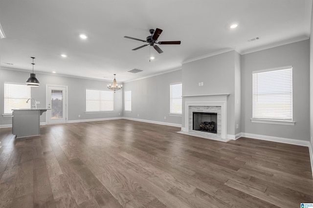 unfurnished living room with ceiling fan with notable chandelier, dark hardwood / wood-style floors, and a healthy amount of sunlight