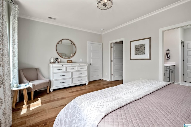 bedroom with crown molding, visible vents, baseboards, and wood finished floors