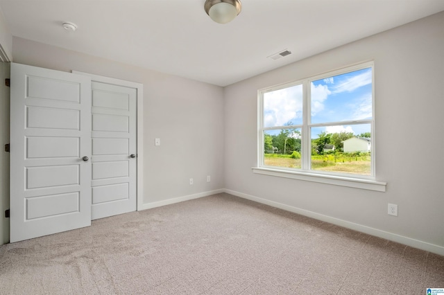unfurnished bedroom with carpet flooring, baseboards, and visible vents