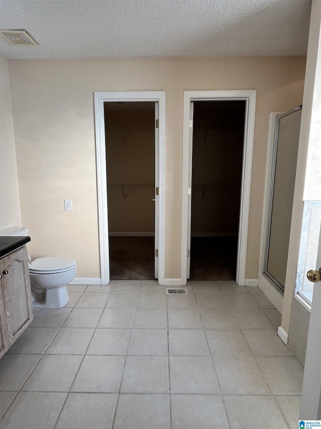 full bathroom featuring vanity, plus walk in shower, tile patterned flooring, and a textured ceiling