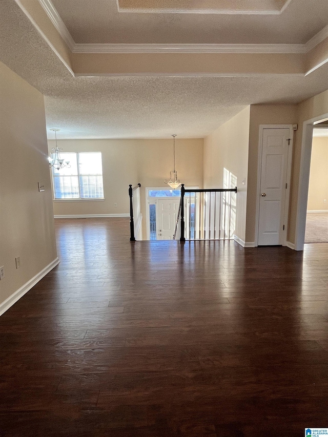 unfurnished room with crown molding, dark wood-type flooring, a notable chandelier, and a tray ceiling