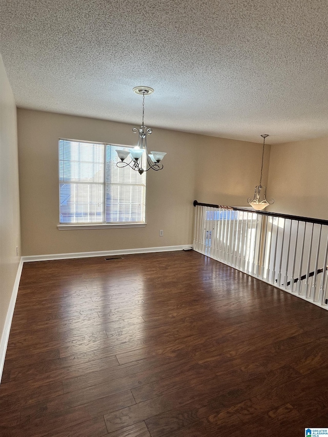 spare room featuring an inviting chandelier and dark wood-type flooring