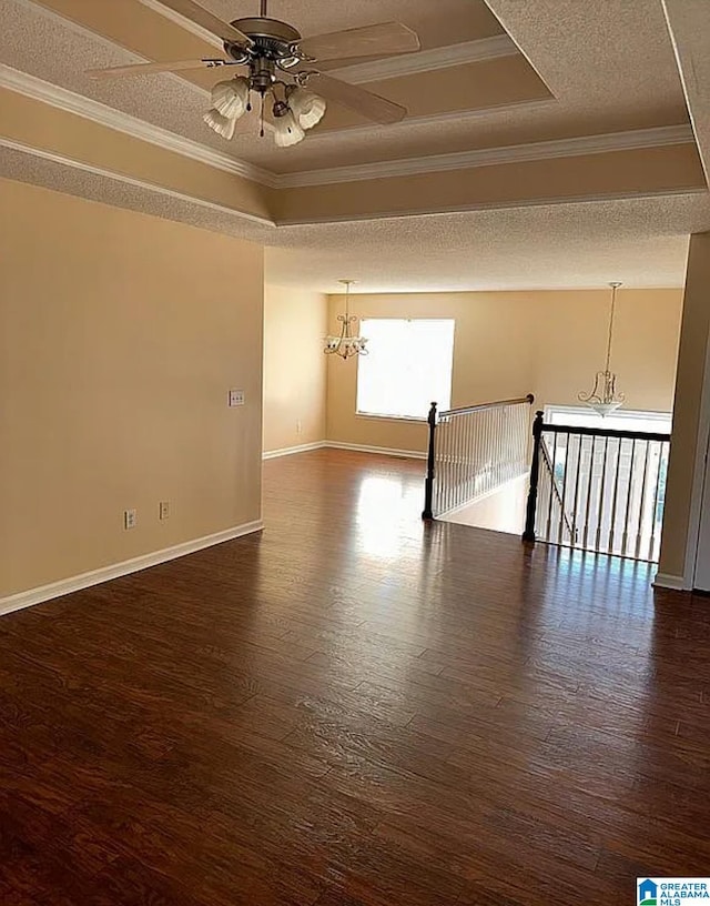 empty room featuring crown molding, dark hardwood / wood-style flooring, a raised ceiling, and a textured ceiling