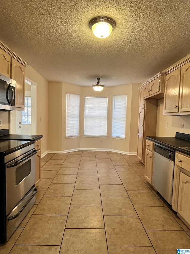 kitchen with light brown cabinetry, light tile patterned floors, stainless steel appliances, and a textured ceiling