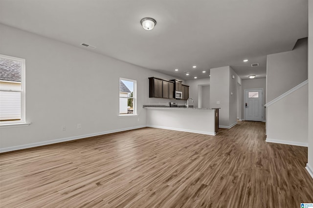 unfurnished living room with sink and light hardwood / wood-style floors