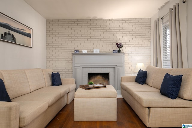 living room featuring dark hardwood / wood-style floors, a brick fireplace, and brick wall