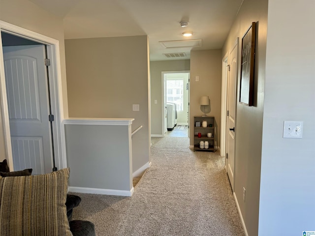 corridor featuring washer / clothes dryer and light colored carpet