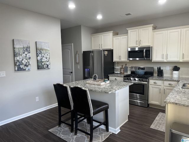 kitchen with white cabinetry, a center island, dark hardwood / wood-style flooring, backsplash, and appliances with stainless steel finishes