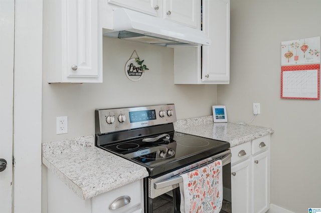 kitchen featuring electric range, white cabinets, and light stone counters