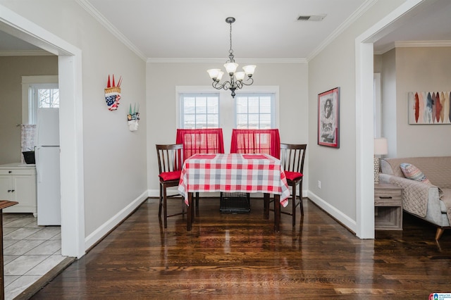 dining room with dark hardwood / wood-style flooring, ornamental molding, and a chandelier