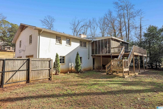 rear view of house featuring a yard, a deck, and a sunroom