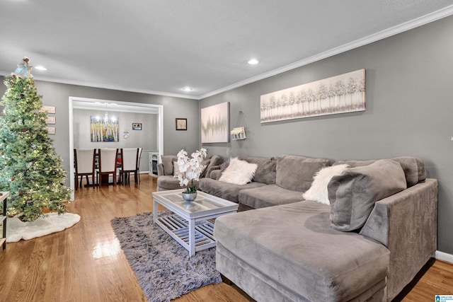 living room featuring a chandelier, crown molding, and wood-type flooring