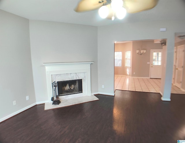 unfurnished living room with a premium fireplace, hardwood / wood-style floors, and ceiling fan with notable chandelier