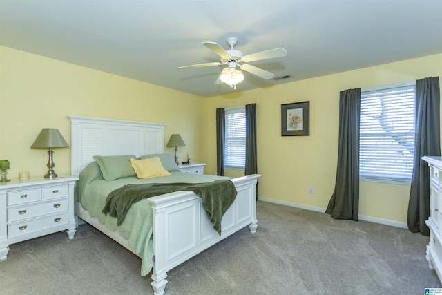 bedroom with multiple windows, light colored carpet, and ceiling fan