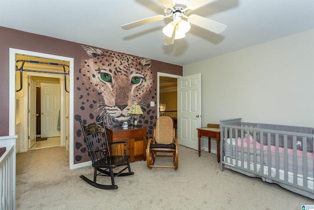 carpeted bedroom featuring ceiling fan and a crib