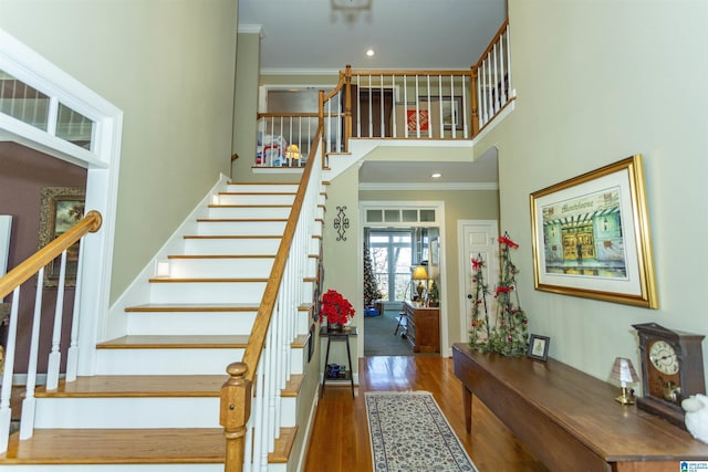 stairs with hardwood / wood-style flooring, ornamental molding, a high ceiling, and french doors