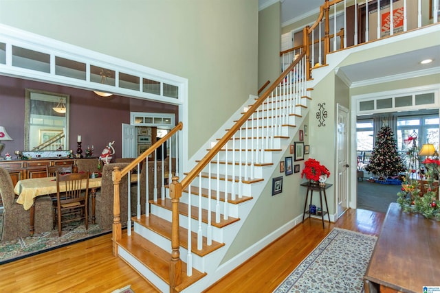 staircase with wood-type flooring and ornamental molding