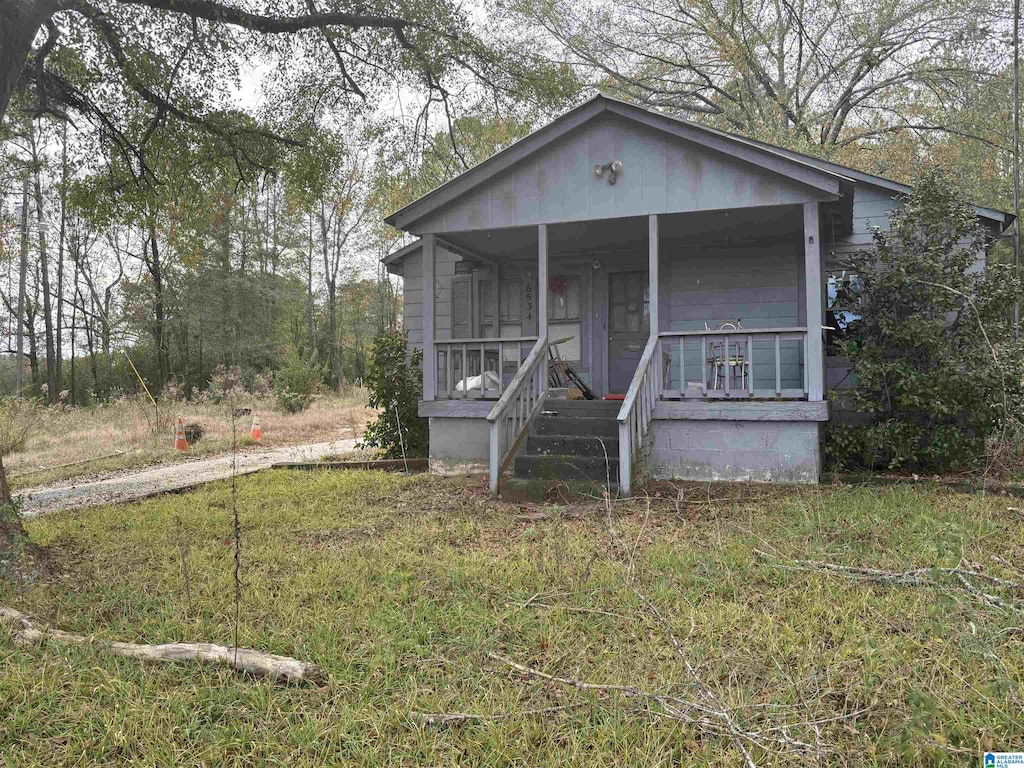 bungalow-style house featuring covered porch and a front yard