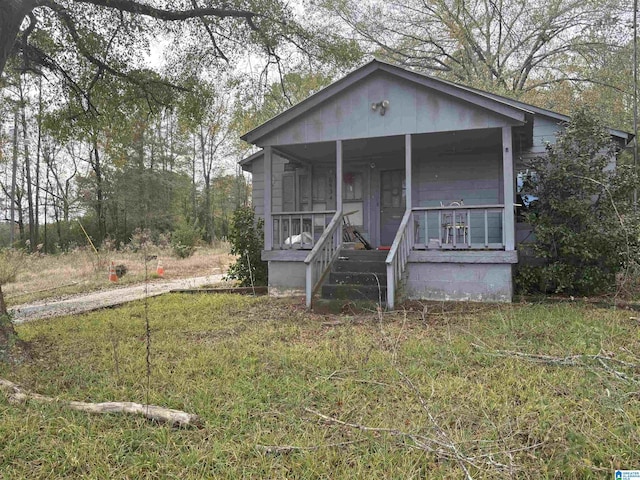 bungalow-style house featuring covered porch and a front yard