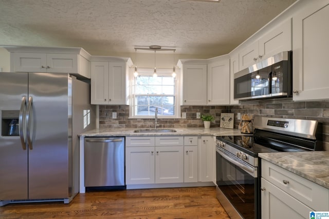 kitchen with sink, a textured ceiling, decorative light fixtures, white cabinetry, and stainless steel appliances