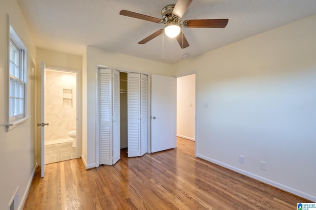 unfurnished bedroom featuring wood-type flooring, ensuite bathroom, and ceiling fan