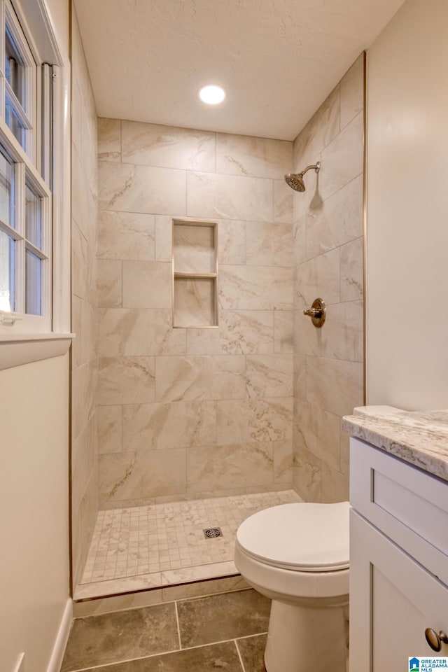 bathroom featuring vanity, toilet, and tiled shower