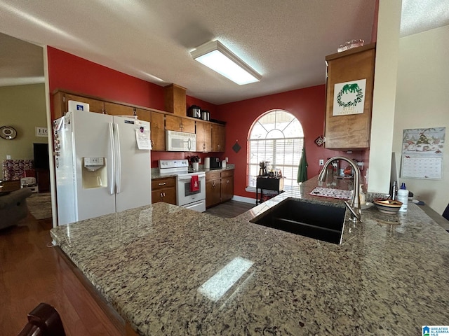 kitchen with kitchen peninsula, sink, white appliances, a textured ceiling, and dark hardwood / wood-style flooring