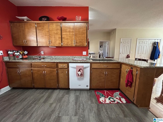 kitchen featuring a textured ceiling, dishwasher, dark hardwood / wood-style flooring, sink, and kitchen peninsula