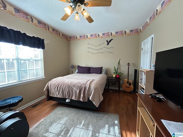 bedroom with ceiling fan, a textured ceiling, and dark hardwood / wood-style floors