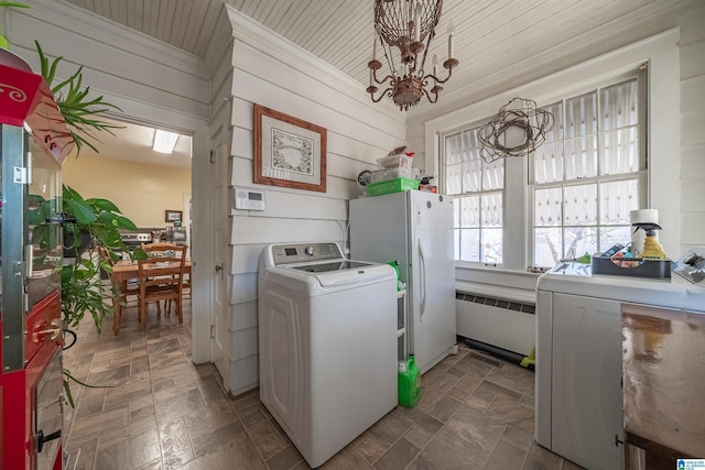 laundry room with radiator heating unit, an inviting chandelier, washer and clothes dryer, and wood walls