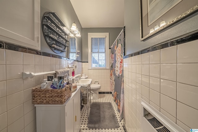 bathroom with tile patterned flooring, sink, toilet, and tile walls