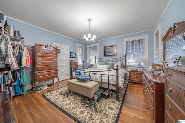 bedroom with ornamental molding, light wood-type flooring, and a notable chandelier