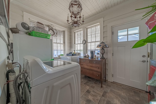 clothes washing area featuring an inviting chandelier and washing machine and clothes dryer