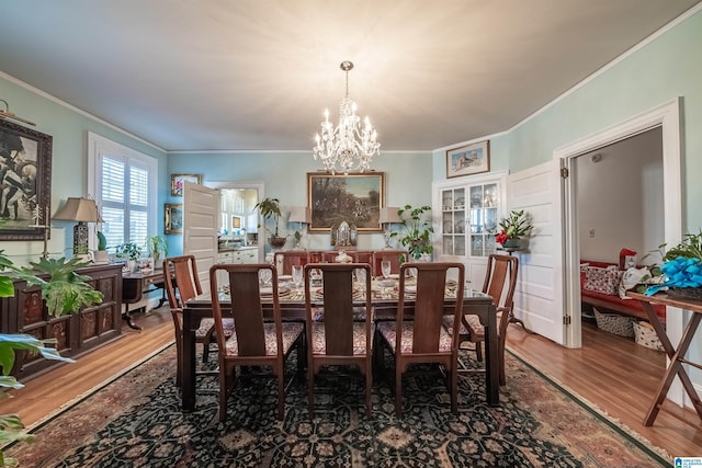 dining space featuring hardwood / wood-style flooring, ornamental molding, and a chandelier