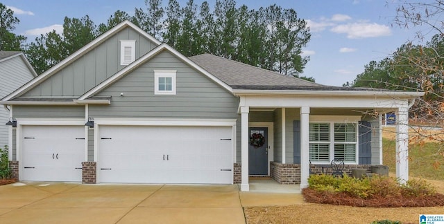 view of front of house featuring brick siding, a porch, board and batten siding, a garage, and driveway