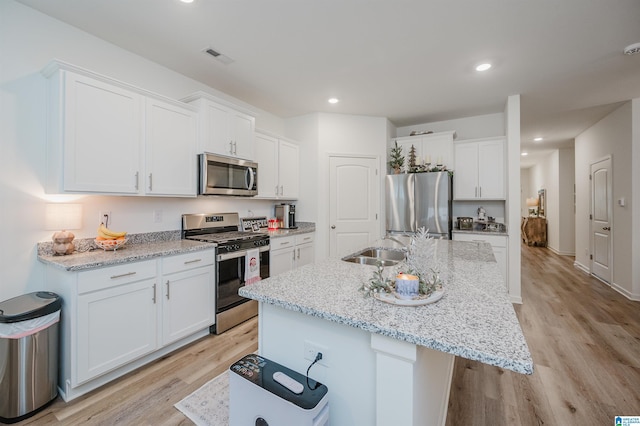 kitchen featuring stainless steel appliances, sink, a center island with sink, light hardwood / wood-style flooring, and white cabinets